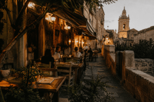 Traditional restaurant terrace in Gozo, Malta with warm evening lighting, rustic tables, and Mediterranean atmosphere.