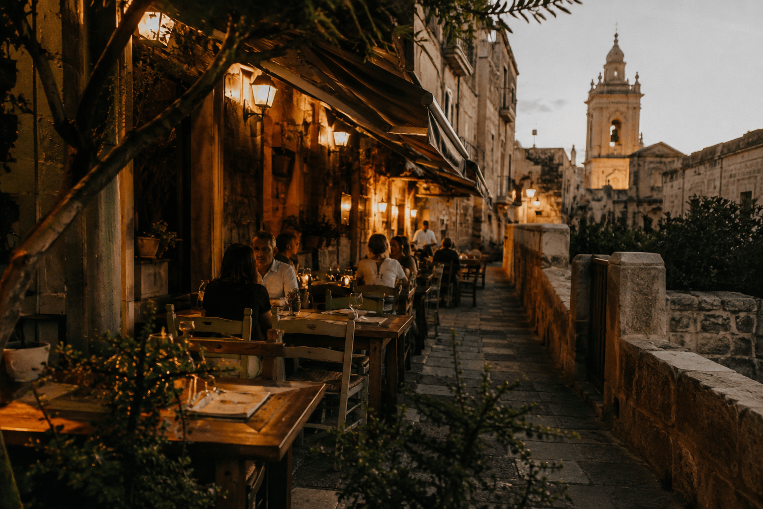 Traditional restaurant terrace in Gozo, Malta with warm evening lighting, rustic tables, and Mediterranean atmosphere.